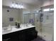 Bright bathroom with double vanity, a large mirror, and a glass-enclosed shower at 777 Star Apple Ln, Las Vegas, NV 89178