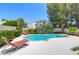 Inviting backyard pool featuring a stone trim, lush landscaping and a lounge area at 8312 Raphael Ct, Las Vegas, NV 89129