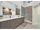 Bright bathroom with a large mirror, granite countertops, and glass-enclosed shower with stone floor at 8370 Plum Creek Ct, Las Vegas, NV 89113