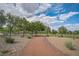 Scenic walking path through a park with lush greenery and trees, under a beautiful cloudy sky at 9053 Starling Wing Pl, Las Vegas, NV 89143