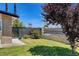 Landscaped side yard featuring a wrought iron fence, lush lawn, and mature trees at 925 Alan Shepard St, Las Vegas, NV 89145