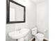 Bathroom featuring a pedestal sink and toilet on wood-look flooring; framed mirror at 981 Leadville Meadows Dr, Henderson, NV 89052