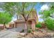 Charming front of the home showcases a two-car garage, covered entryway, and established landscaping with mature trees at 9906 Stiges St, Las Vegas, NV 89178