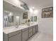 Bright bathroom featuring a double sink vanity with gray cabinets and decorative mirrors and wall art at 10140 Magnolia Creek St, Las Vegas, NV 89141