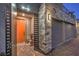 Modern home's entry with an orange door, stone accents, and three-car garage at 10140 Magnolia Creek St, Las Vegas, NV 89141