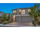 Modern home featuring a stone facade, balcony, and two-car garage, enhanced by professional landscaping at 10140 Magnolia Creek St, Las Vegas, NV 89141