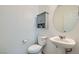 Cozy half-bathroom features a pedestal sink, round mirror, and a charming gray cabinet above the toilet at 10650 Sariah Skye Ave, Las Vegas, NV 89166
