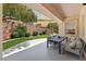 Charming covered patio with seating and dining, overlooking the grassy backyard with brick wall at 10814 Franklin Hills Ave, Las Vegas, NV 89135