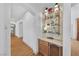 Hallway bar with glass shelving, built in mini fridge and light wood cabinets at 10814 Franklin Hills Ave, Las Vegas, NV 89135