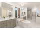 Luxurious bathroom with dual vanities, a soaking tub, chandelier and glass-enclosed shower at 11271 Winter Cottage Pl, Las Vegas, NV 89135