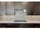Detailed shot of a modern kitchen with a stainless steel range hood and mosaic backsplash at 11280 Granite Ridge Dr # 1009, Las Vegas, NV 89135