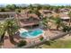 A high angle view shows a large kidney shaped pool, desert landscaping, and mature palm trees at 1587 Bermuda Dunes Dr, Boulder City, NV 89005