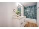 Modern bathroom with blue-tiled shower, quartz countertop vanity, and wood-look flooring at 1600 E Mcdonald Ave, North Las Vegas, NV 89030