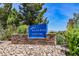 The entrance of the Aliante Golf Club showcases a blue sign with rock decor, lush plants, and trees around the outdoor area at 2008 Royal Gardens Pl, North Las Vegas, NV 89084