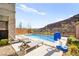 Inviting backyard pool featuring lounge chairs, a basketball hoop, privacy fence, and views of the surrounding hills at 41 Strada Moscato, Henderson, NV 89011