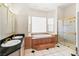 Primary bath with a corner tub, glass block window, a walk-in shower, and dual sinks at 4545 W Agate Ave, Las Vegas, NV 89139
