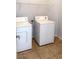 This laundry room features a washer, dryer, tile floor, and a shelf for storage at 5004 Wayfaring Tree Ave, Las Vegas, NV 89131