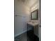 Half bath with dark cabinet vanity, white sink, updated lighting, and black tile flooring at 5256 Harvest Breeze Rd, Las Vegas, NV 89118
