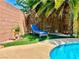 Lounge chair by backyard pool with artificial grass and mature palm trees at 5368 Regal Ave, Las Vegas, NV 89146
