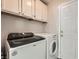 Functional laundry room with a modern, front-loading washer and dryer and overhead cabinets at 5489 Royal Vista Ln, Las Vegas, NV 89149
