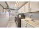 Functional laundry room with sink, countertop space, washer, dryer and storage shelves and cabinets at 6103 Sundown Crest St, Las Vegas, NV 89113