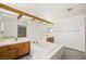 Bright bathroom featuring a soaking tub, wood cabinets, and unique mirror with wood accent at 615 Cervantes Dr, Henderson, NV 89014