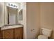 Half bathroom with oak cabinets, stone-look countertop and a rectangular mirror above the sink at 6241 Overhang Ave, Henderson, NV 89011