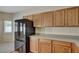 Bright kitchen showcasing oak cabinetry, stone-look countertops, and a sleek black refrigerator near the breakfast nook at 6241 Overhang Ave, Henderson, NV 89011