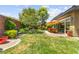 Well-maintained backyard with mature trees, green grass, and an umbrella-shaded outdoor dining area at 6810 Silver Crescent St, Las Vegas, NV 89148