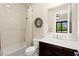 Well-lit bathroom features a shower-tub combo, decorative wreath, and dark wood vanity at 6810 Silver Crescent St, Las Vegas, NV 89148