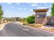 Community entrance with stone signage, lush landscaping, and paved road at 6810 Silver Crescent St, Las Vegas, NV 89148