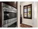 Stainless steel double oven adjacent to dark wood cabinetry with interior view to a window at 6810 Silver Crescent St, Las Vegas, NV 89148