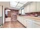 Cozy kitchenette with tiled floor, brick accents, and white cabinetry under a bright skylight at 7898 Wishing Well Rd, Las Vegas, NV 89123