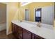 Bright bathroom featuring dual sinks with gold fixtures, white countertops, and wood cabinets at 9077 Creed Mountain Pl, Las Vegas, NV 89178