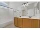 Bathroom with dual sinks, wood cabinets, a large mirror, and a shower-tub combo at 10062 Aspen Rose St # 103, Las Vegas, NV 89183