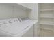 Convenient laundry room features a washer, dryer, and shelving for storage at 10062 Aspen Rose St # 103, Las Vegas, NV 89183
