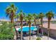 Community pool surrounded by palm trees and a black metal fence on a sunny day at 10062 Aspen Rose St # 103, Las Vegas, NV 89183