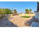 Spacious backyard featuring sand and a rectangular patch of artificial grass, surrounded by a wooden fence and lush trees at 1411 Norman Ave, Las Vegas, NV 89104