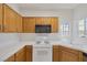 Efficient kitchen featuring white appliances, a tile backsplash, and natural wood cabinetry at 1830 N Buffalo Dr # 2024, Las Vegas, NV 89128