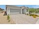 Exterior view of home featuring a paver driveway, two car garage and desert landscaping at 3024 River Brook Ct, Las Vegas, NV 89139