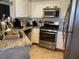 Modern kitchen with stone countertops, stainless steel appliances, tiled backsplash and white cabinets at 3320 S Fort Apache Rd # 139, Las Vegas, NV 89117