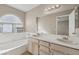 Bathroom featuring a double sink vanity, large mirror, tub, and a window with natural light at 5636 Royal Castle Ln, Las Vegas, NV 89130