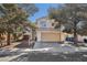 Charming two-story home featuring a beige exterior, two-car garage, and mature landscaping with shade trees at 5636 Royal Castle Ln, Las Vegas, NV 89130