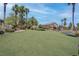 Well-maintained community space with green grass and mature palm trees under a blue sky at 7120 Bear Paw Creek St # 101, Las Vegas, NV 89149