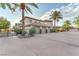 A tan stucco home with a three-car garage and a long driveway surrounded by mature landscaping at 743 N Orleans St, Henderson, NV 89015