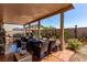 Covered patio space with fire pit, lounge seating, dining furniture, and a desert landscape at 7824 Warm Winds St, North Las Vegas, NV 89084