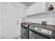 Bright laundry room with modern black washer and dryer and upper cabinets at 818 Grape Vine Ave, Henderson, NV 89002