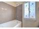 Bathroom with a bathtub, shower head, tiled wall and decorated window at 8565 Silver Coast St, Las Vegas, NV 89139