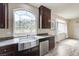 Close-up of a kitchen sink and counter with dark wood cabinets and a large window with views of the desert landscape at 8565 Silver Coast St, Las Vegas, NV 89139