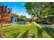 Expansive backyard with a sparkling pool, lush green lawn, mature trees, and a charming pool house at 2001 Silver Ave, Las Vegas, NV 89102